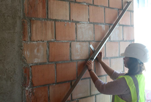 De vlakheid van een muur uit metselwerk wordt gemeten met een lat van 2 m